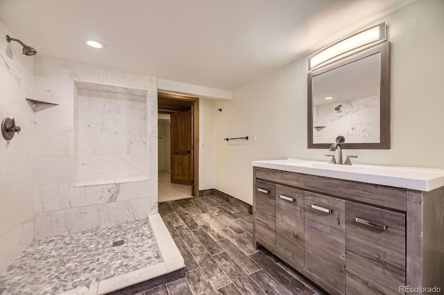 bathroom featuring recessed lighting, tiled shower, vanity, and wood finish floors