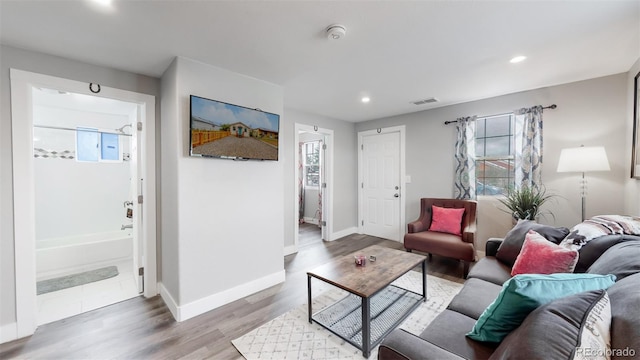 living room featuring baseboards, visible vents, a wealth of natural light, and recessed lighting