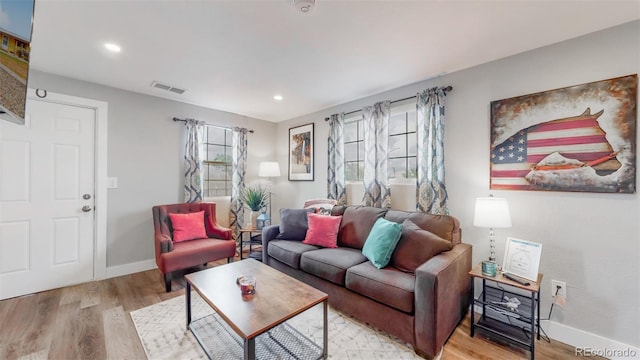 living room featuring visible vents, baseboards, and light wood-type flooring