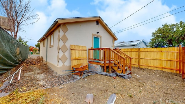 back of house with stucco siding and fence