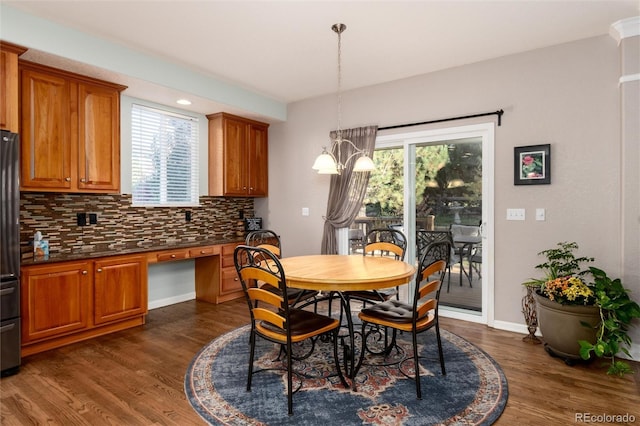 dining area featuring a healthy amount of sunlight, a notable chandelier, and dark hardwood / wood-style flooring