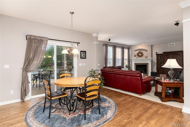 dining area featuring visible vents, a fireplace, baseboards, and wood finished floors