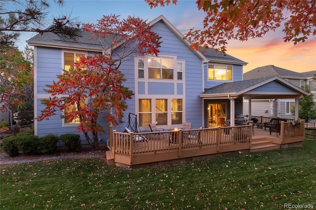 back house at dusk with a yard and a wooden deck