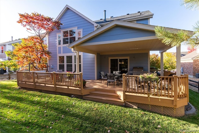 back of property with outdoor dining space, a yard, and a wooden deck