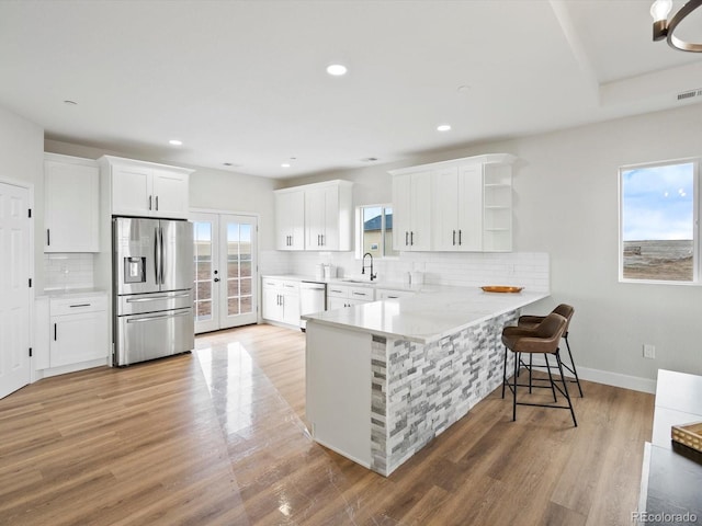 kitchen featuring open shelves, a sink, stainless steel fridge, a peninsula, and white cabinetry