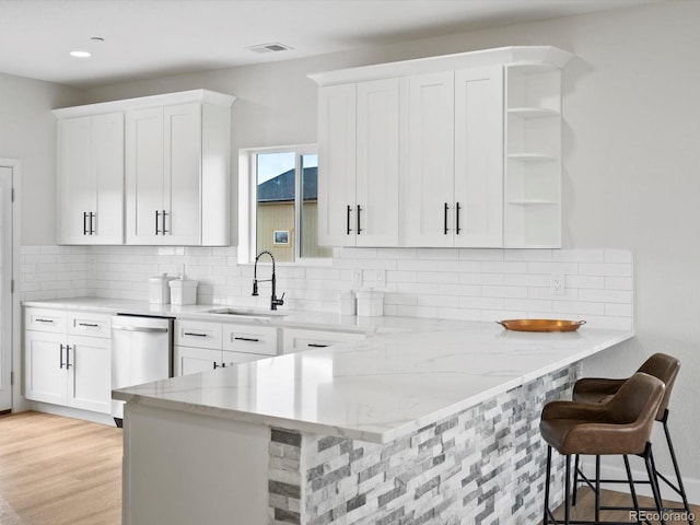 kitchen featuring white cabinets, stainless steel dishwasher, visible vents, and a sink