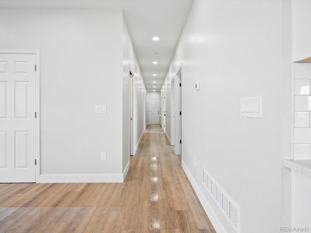 hallway featuring baseboards, visible vents, recessed lighting, and light wood-style floors