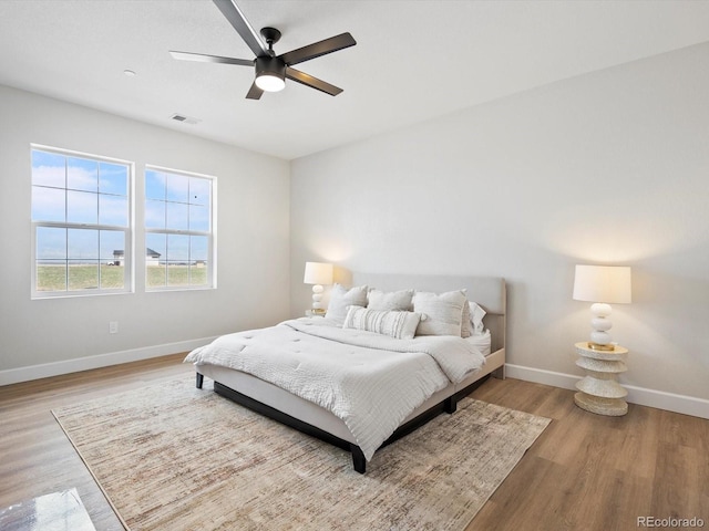 bedroom with baseboards, a ceiling fan, visible vents, and light wood-type flooring
