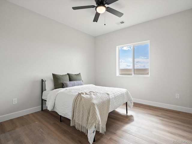 bedroom with baseboards, a ceiling fan, wood finished floors, and visible vents