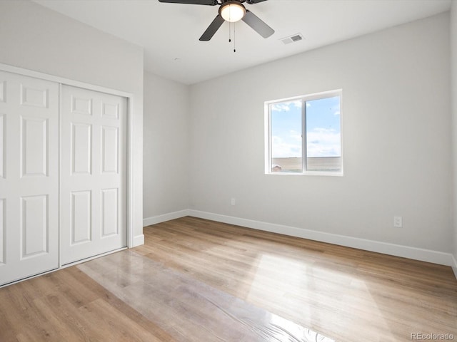 unfurnished bedroom featuring a closet, ceiling fan, light wood-style flooring, baseboards, and visible vents