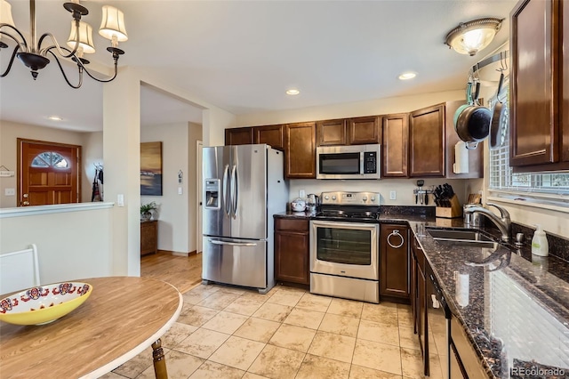 kitchen featuring a chandelier, dark stone counters, recessed lighting, appliances with stainless steel finishes, and a sink