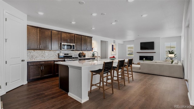 kitchen with sink, stainless steel appliances, backsplash, a kitchen bar, and a kitchen island with sink