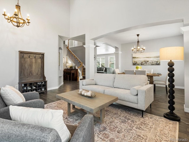 living room with an inviting chandelier, decorative columns, dark hardwood / wood-style floors, and a high ceiling