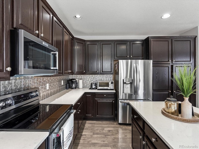 kitchen with tasteful backsplash, light stone counters, dark brown cabinets, light hardwood / wood-style flooring, and stainless steel appliances