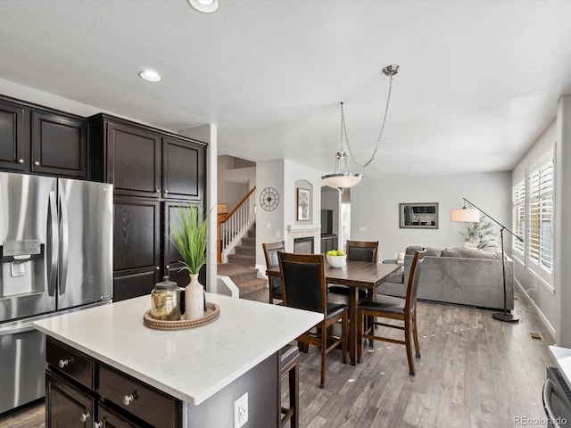 kitchen featuring pendant lighting, stainless steel fridge, a breakfast bar, a center island, and wood-type flooring