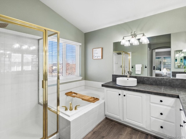 bathroom with independent shower and bath, vaulted ceiling, hardwood / wood-style floors, and vanity