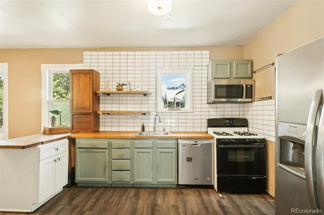 kitchen with sink, dark wood-type flooring, wood counters, tasteful backsplash, and appliances with stainless steel finishes