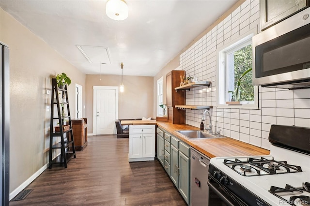 kitchen with dark wood-type flooring, sink, appliances with stainless steel finishes, butcher block countertops, and decorative light fixtures