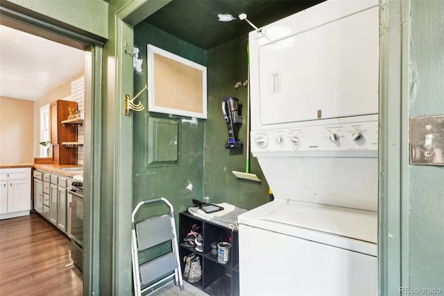 laundry room featuring hardwood / wood-style flooring and stacked washer / dryer