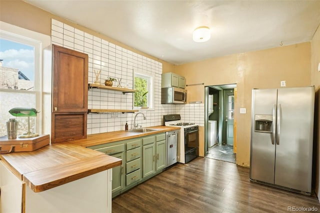 kitchen with sink, wood counters, green cabinets, decorative backsplash, and appliances with stainless steel finishes