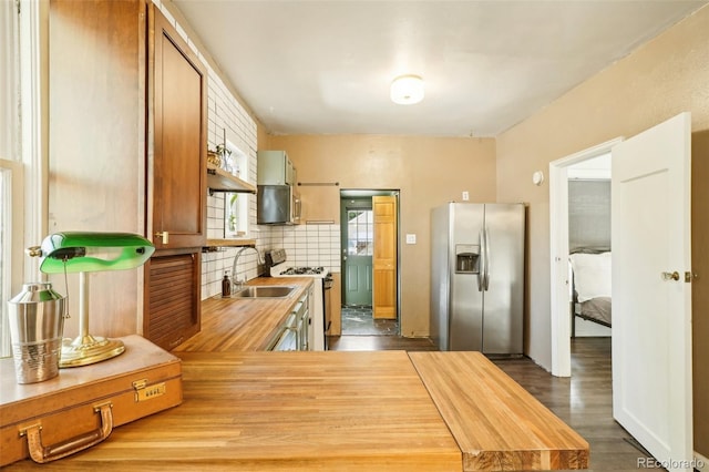 kitchen featuring tasteful backsplash, stainless steel appliances, sink, hardwood / wood-style floors, and butcher block counters