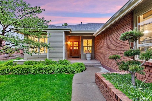 13 Pinyon Pine Rd, Littleton, CO 80127 - exterior entry at dusk featuring brick siding and roof with shingles