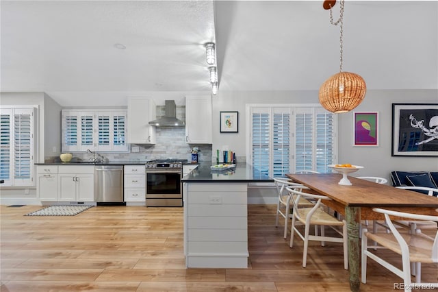13 Pinyon Pine Rd, Littleton, CO 80127 - kitchen with appliances with stainless steel finishes, wall chimney range hood, dark countertops, and white cabinetry