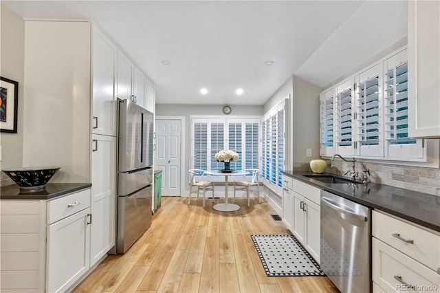 13 Pinyon Pine Rd, Littleton, CO 80127 - kitchen featuring stainless steel appliances, dark countertops, light wood-style floors, a sink, and recessed lighting