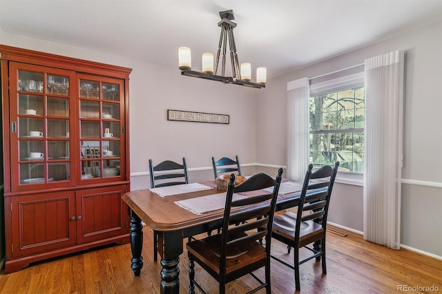 dining area featuring light wood-style flooring, baseboards, and a chandelier