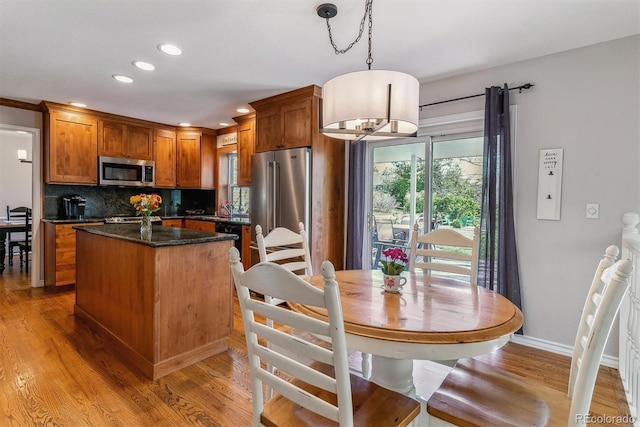 kitchen with stainless steel appliances, a center island, light wood finished floors, backsplash, and recessed lighting