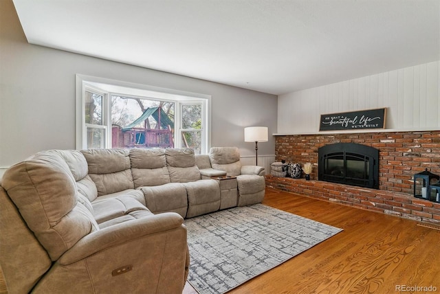 living room featuring wood finished floors and a brick fireplace
