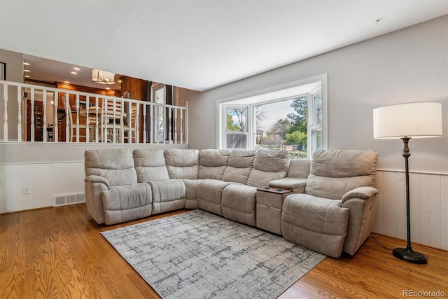 living room featuring wood finished floors, a wainscoted wall, and a chandelier