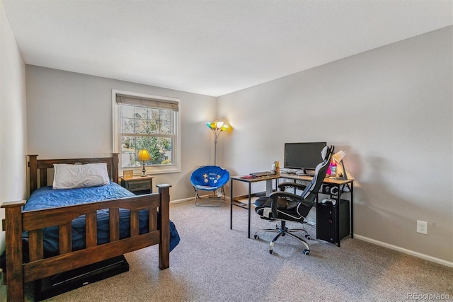 carpeted bedroom with baseboards and a desk