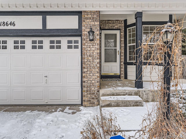 snow covered property entrance featuring a garage