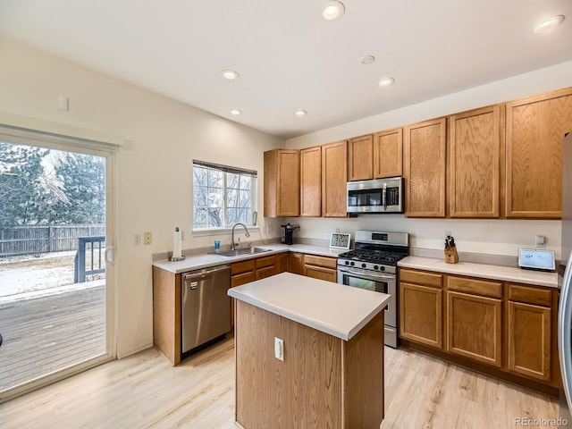 kitchen with a center island, stainless steel appliances, light wood-type flooring, and sink