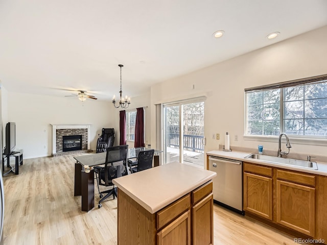 kitchen featuring a brick fireplace, a kitchen island, sink, dishwasher, and pendant lighting