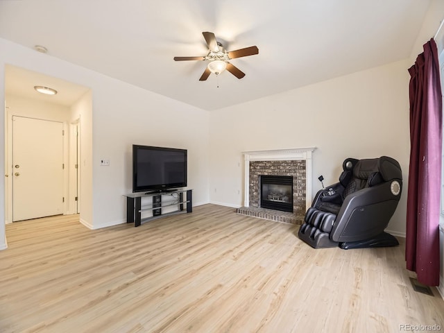 living room featuring a fireplace, light hardwood / wood-style flooring, vaulted ceiling, and ceiling fan