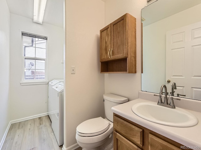 bathroom featuring hardwood / wood-style flooring, washing machine and dryer, vanity, and toilet