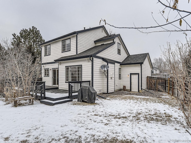 snow covered back of property featuring a wooden deck