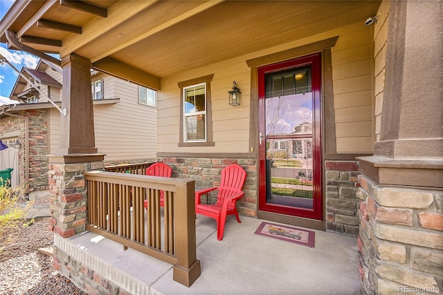 view of exterior entry with stone siding and covered porch