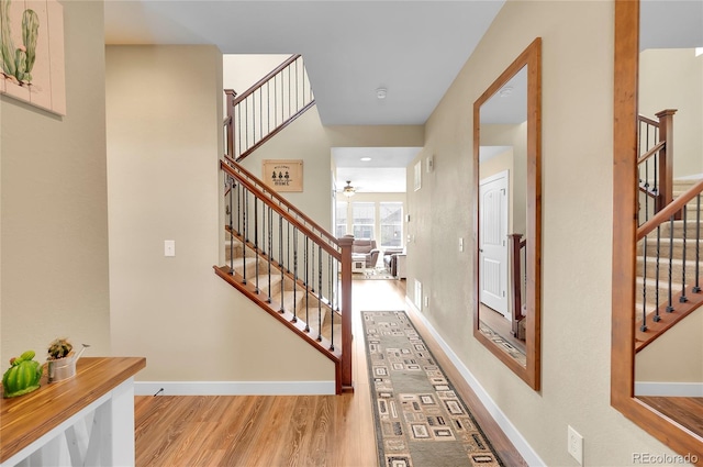 corridor featuring stairway, baseboards, and wood finished floors
