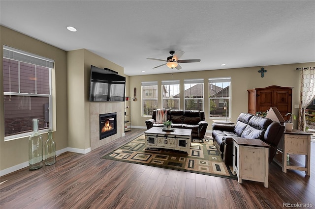 living room featuring a tile fireplace, baseboards, and wood finished floors