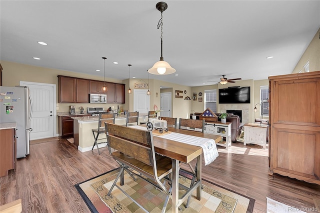 dining space featuring a fireplace, dark wood finished floors, ceiling fan, and recessed lighting
