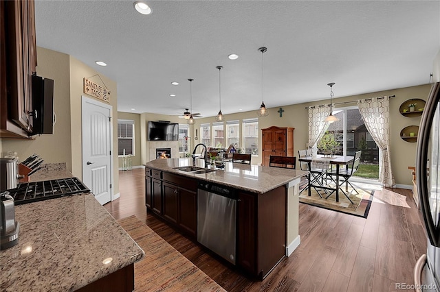 kitchen with dark wood finished floors, dark brown cabinets, dishwasher, a sink, and open floor plan