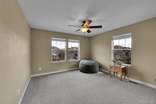 living area featuring carpet floors, ceiling fan, and a healthy amount of sunlight