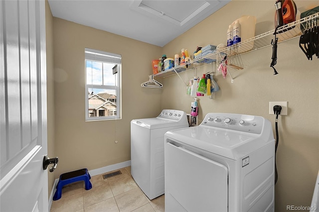 laundry room featuring laundry area, visible vents, light tile patterned floors, washing machine and clothes dryer, and baseboards