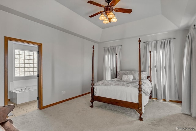 bedroom featuring ensuite bath, ceiling fan, a raised ceiling, and light colored carpet