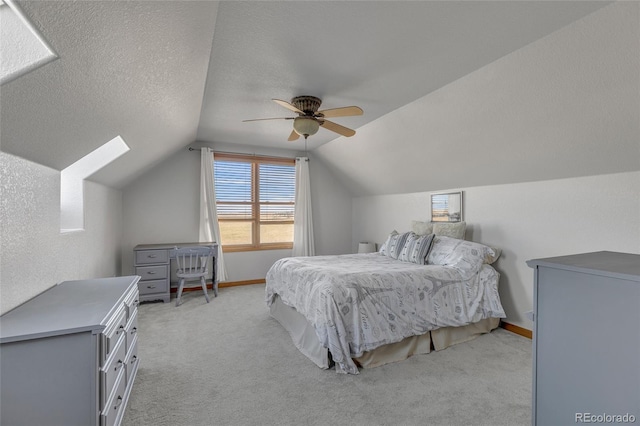 bedroom featuring lofted ceiling with skylight, ceiling fan, light carpet, and a textured ceiling