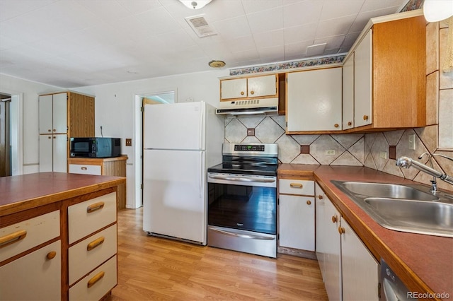 5818 S Skyline Dr, Evergreen, CO 80439 - kitchen with appliances with stainless steel finishes, under cabinet range hood, light wood-style floors, dark countertops, and decorative backsplash