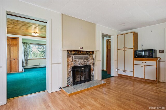 5818 S Skyline Dr, Evergreen, CO 80439 - unfurnished living room featuring light wood-type flooring, a stone fireplace, crown molding, and baseboard heating